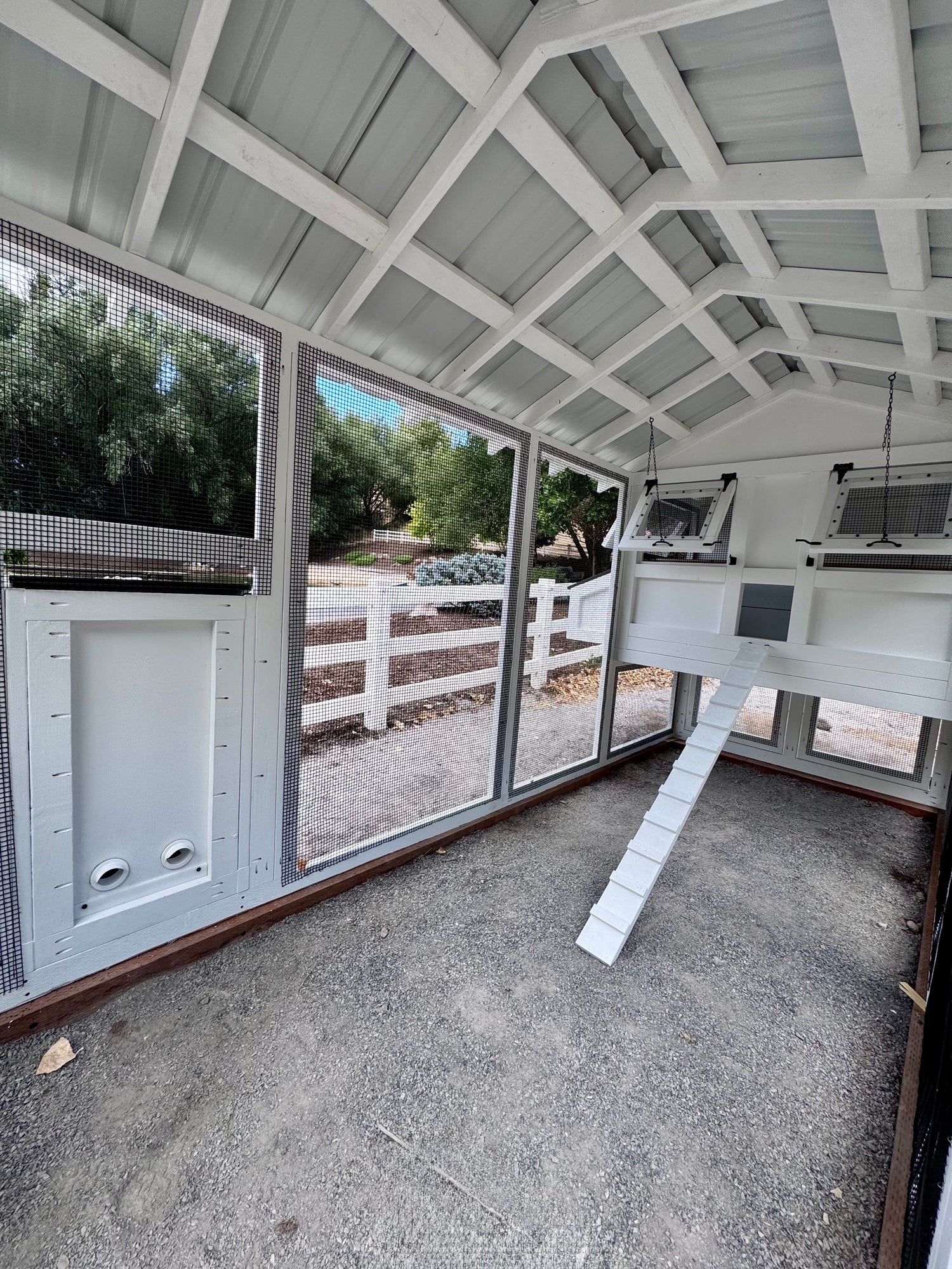 Luxury, custom-built chicken coop set on a modern farm property, designed with a fully enclosed run, automatic chicken feeder, and elevated hen house. A large flock of chickens easily flourishes within a luxury chicken coop such as this without risk of predators, making for happy chickens and keepers alike.